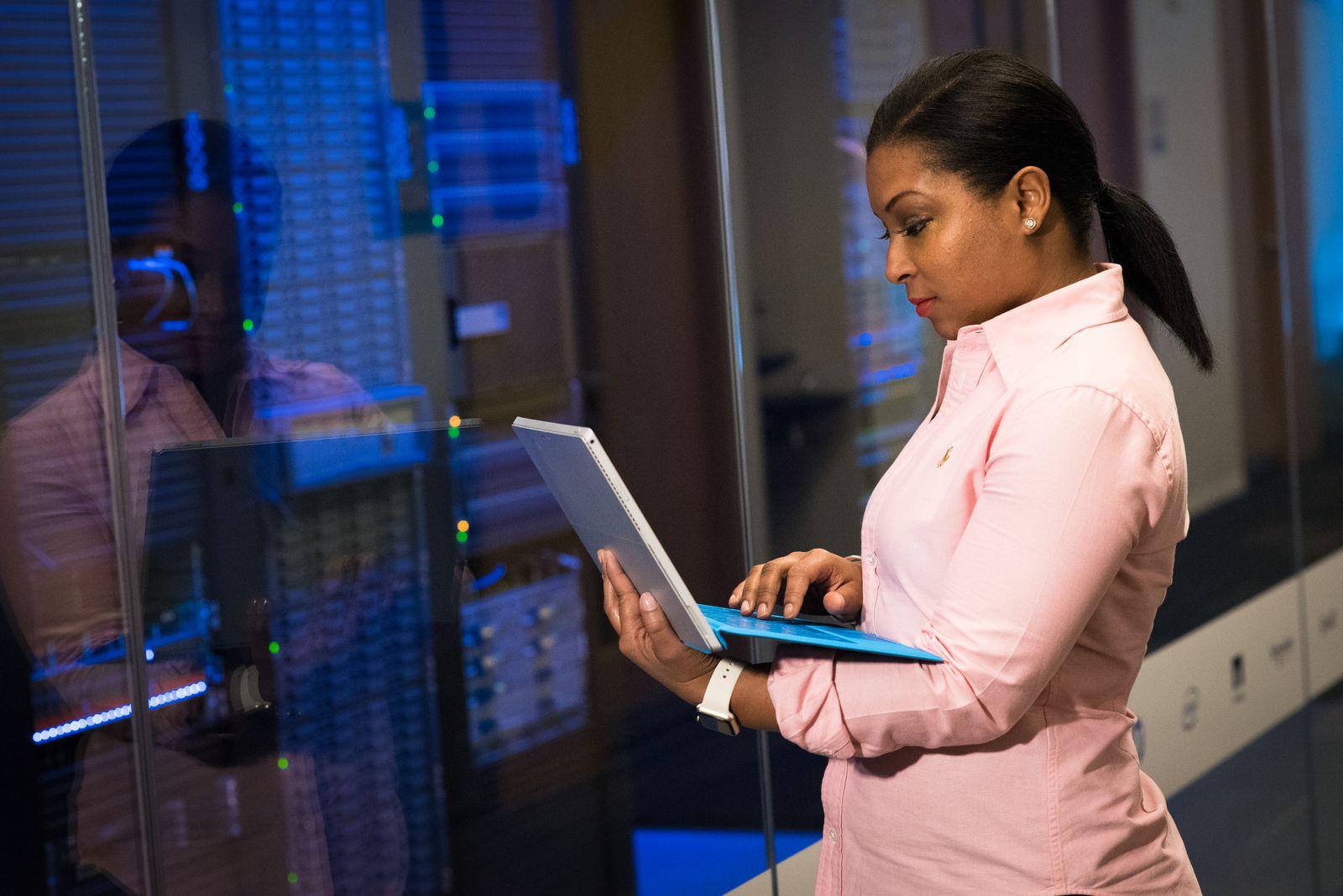 A software engineer working on a laptop in a server room