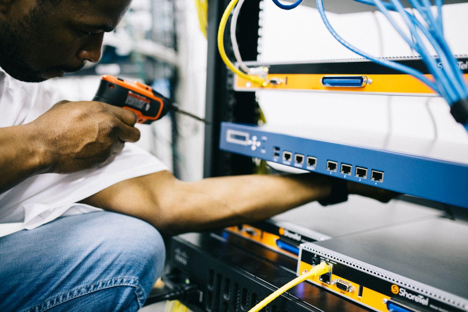 A field technician working on hardware with a screwdriver