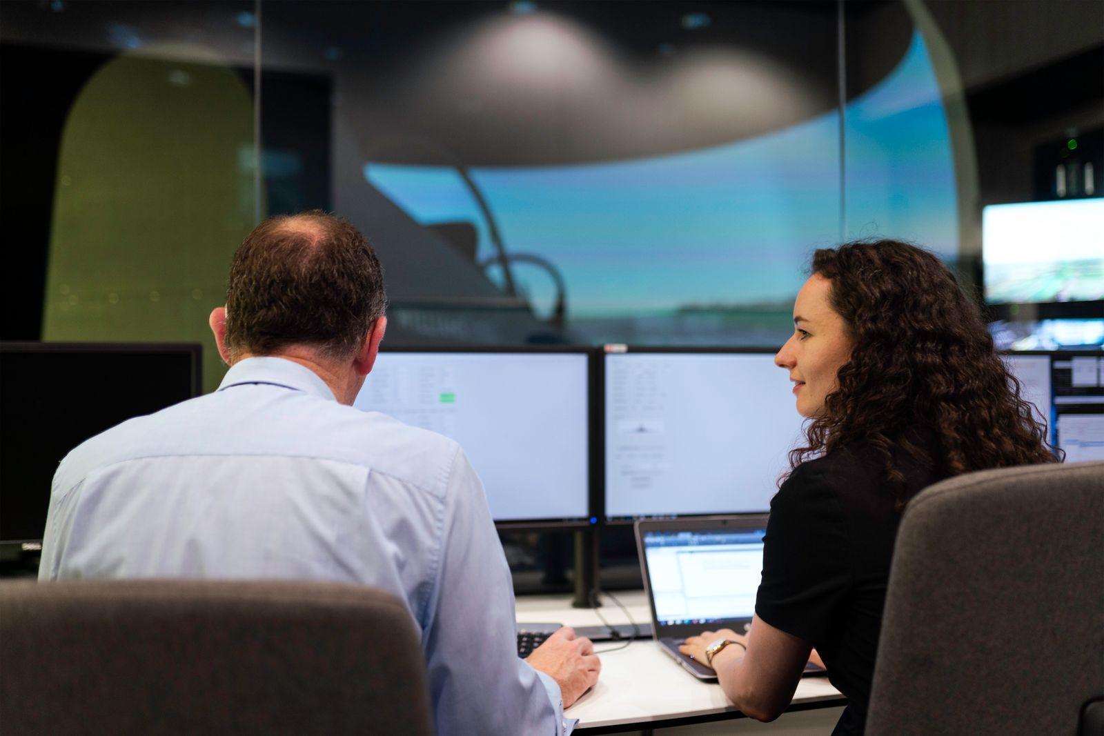 Two engineers working together on a computer simulation in a control room