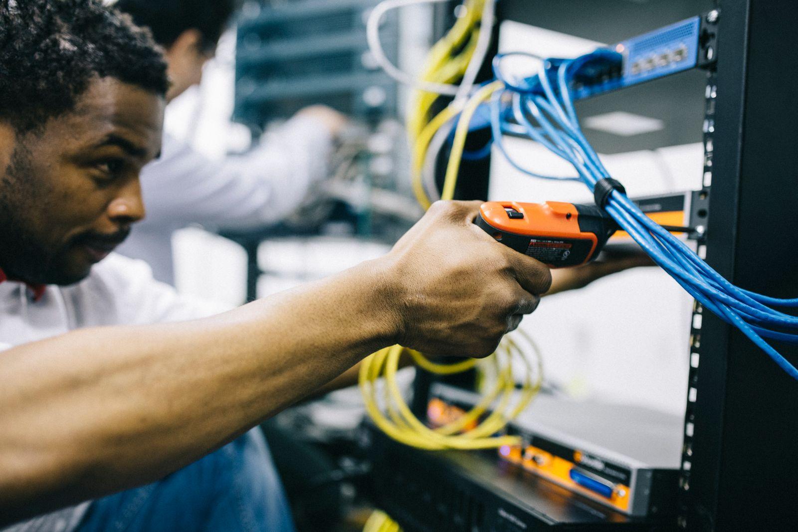 An engineer repairing equipment with an electric screwdriver