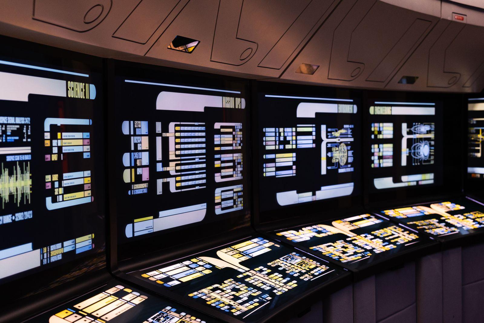 A high-tech command center with illuminated digital monitoring screens