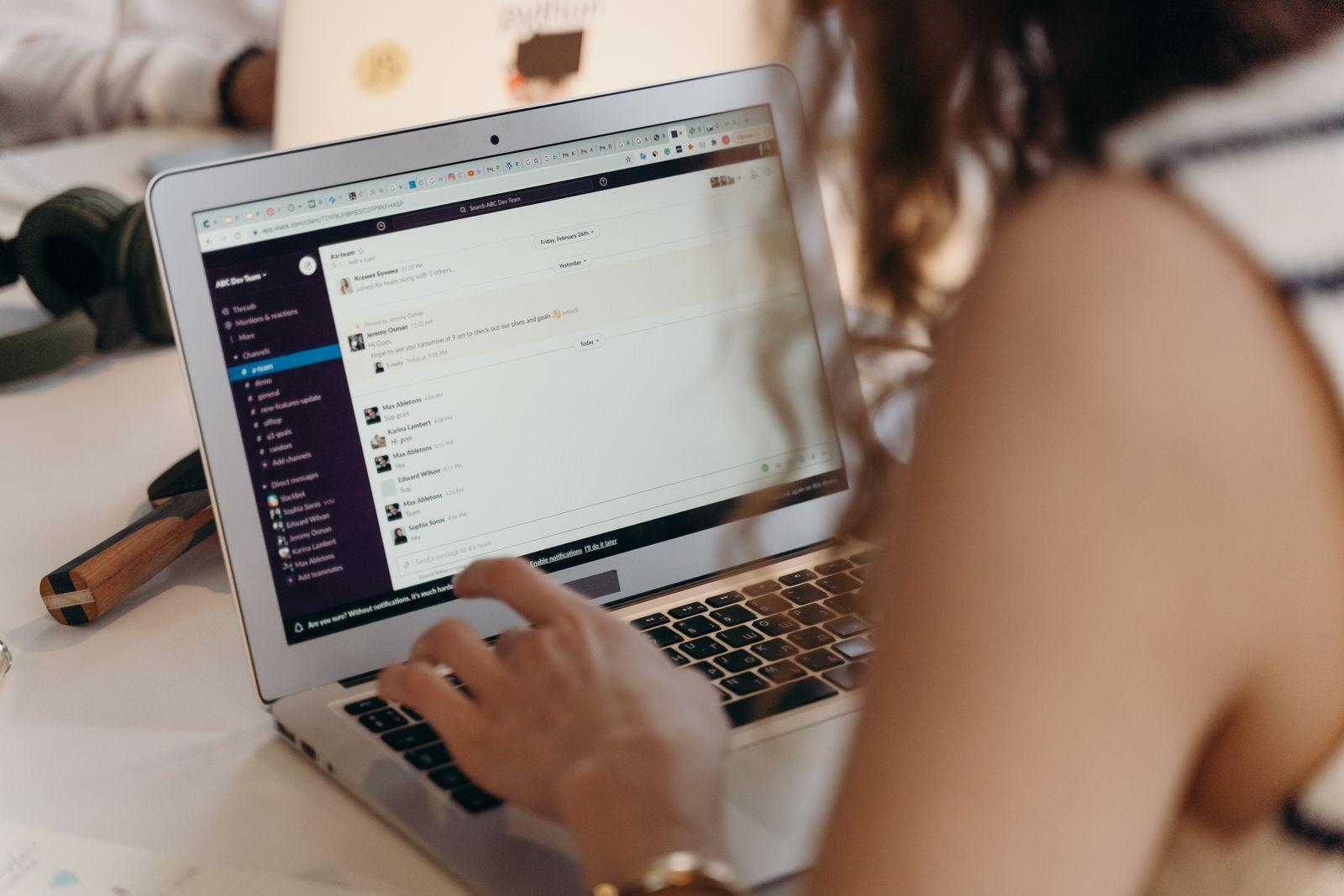 A businesswoman typing on a laptop in a bright office setting