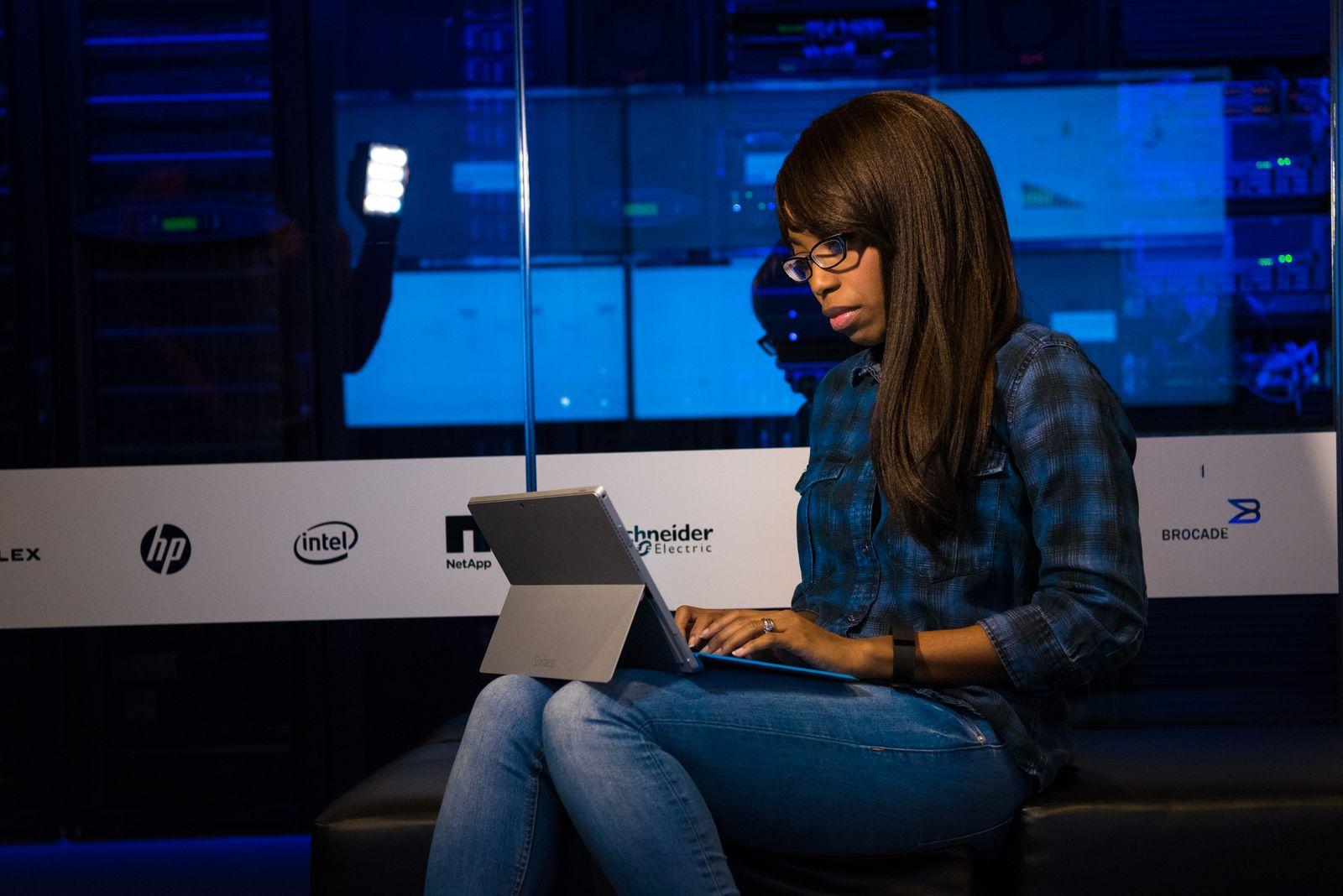 An IT professional working intently on a laptop in a modern data center