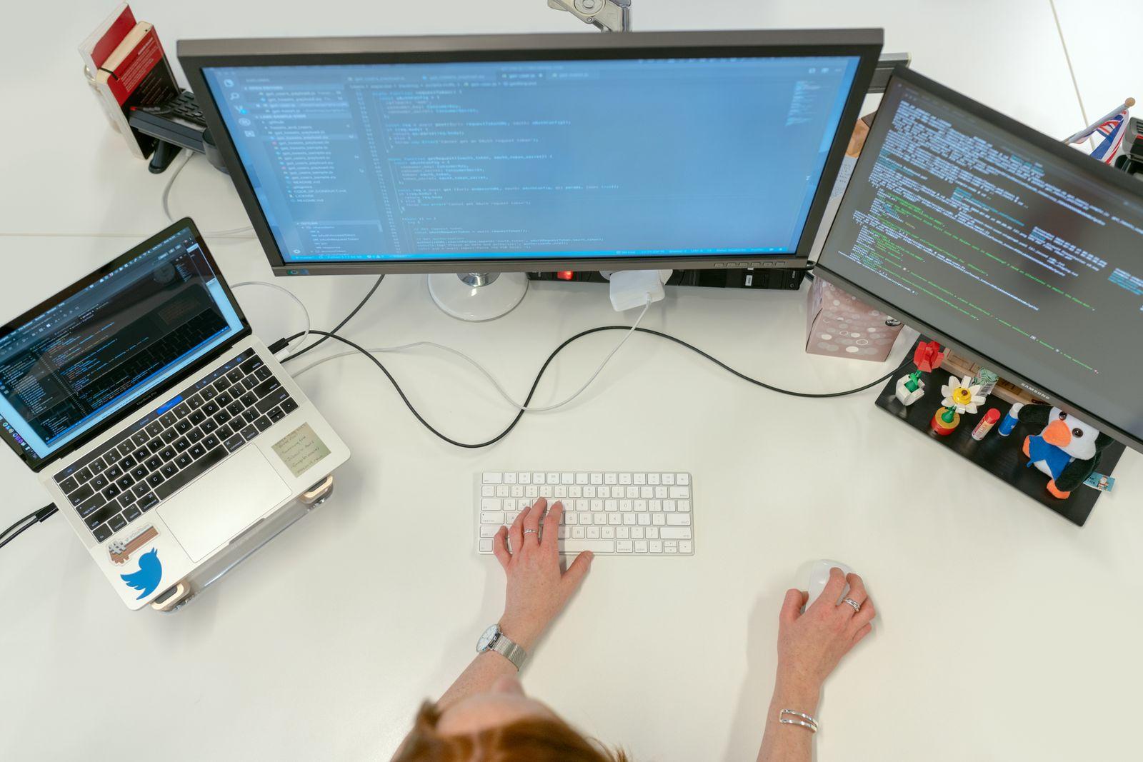 A software engineer coding on dual monitors and a laptop