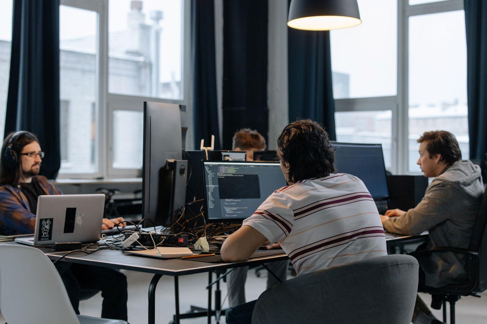 A team of IT professionals collaborating together at computers in a modern office